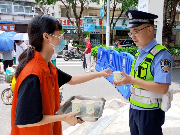 ▲志愿者為值守高考路口的交警送上消暑飲品.jpg